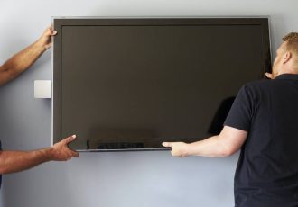 Two Men Fitting Flat Screen Television To Wall